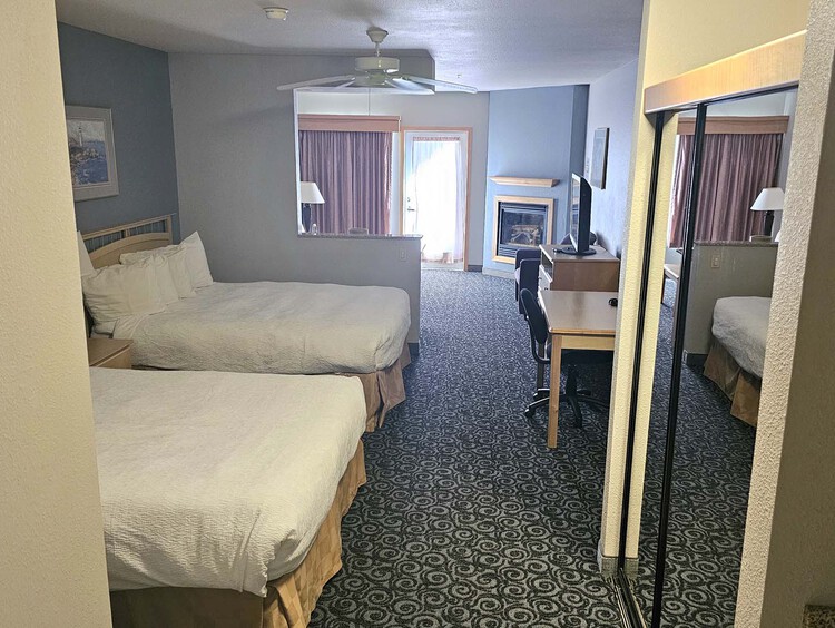 Two queen beds with dresser, work desk, and side table and lamp