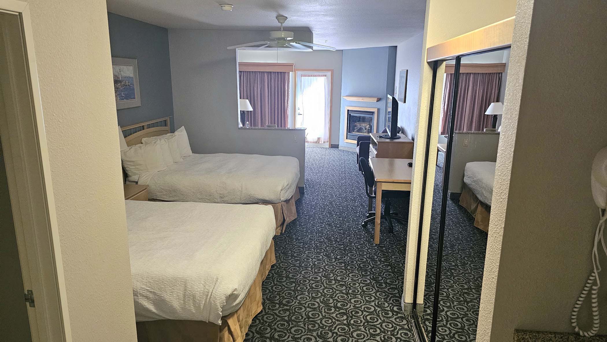 Two queen beds with dresser, work desk, and side table and lamp