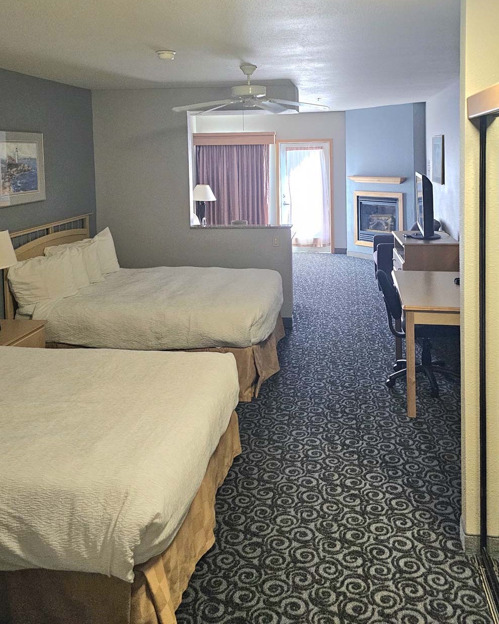 Two queen beds with dresser, work desk, and side table and lamp
