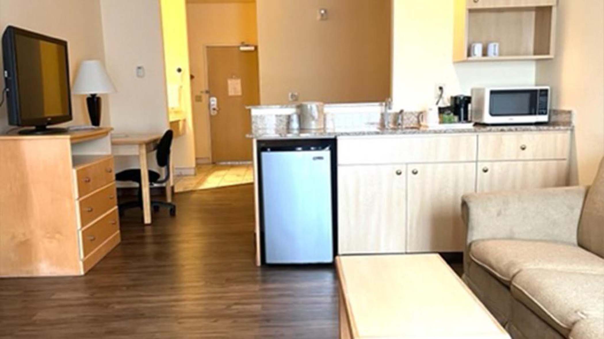 Sofa, table, tv and microwave with a fridge