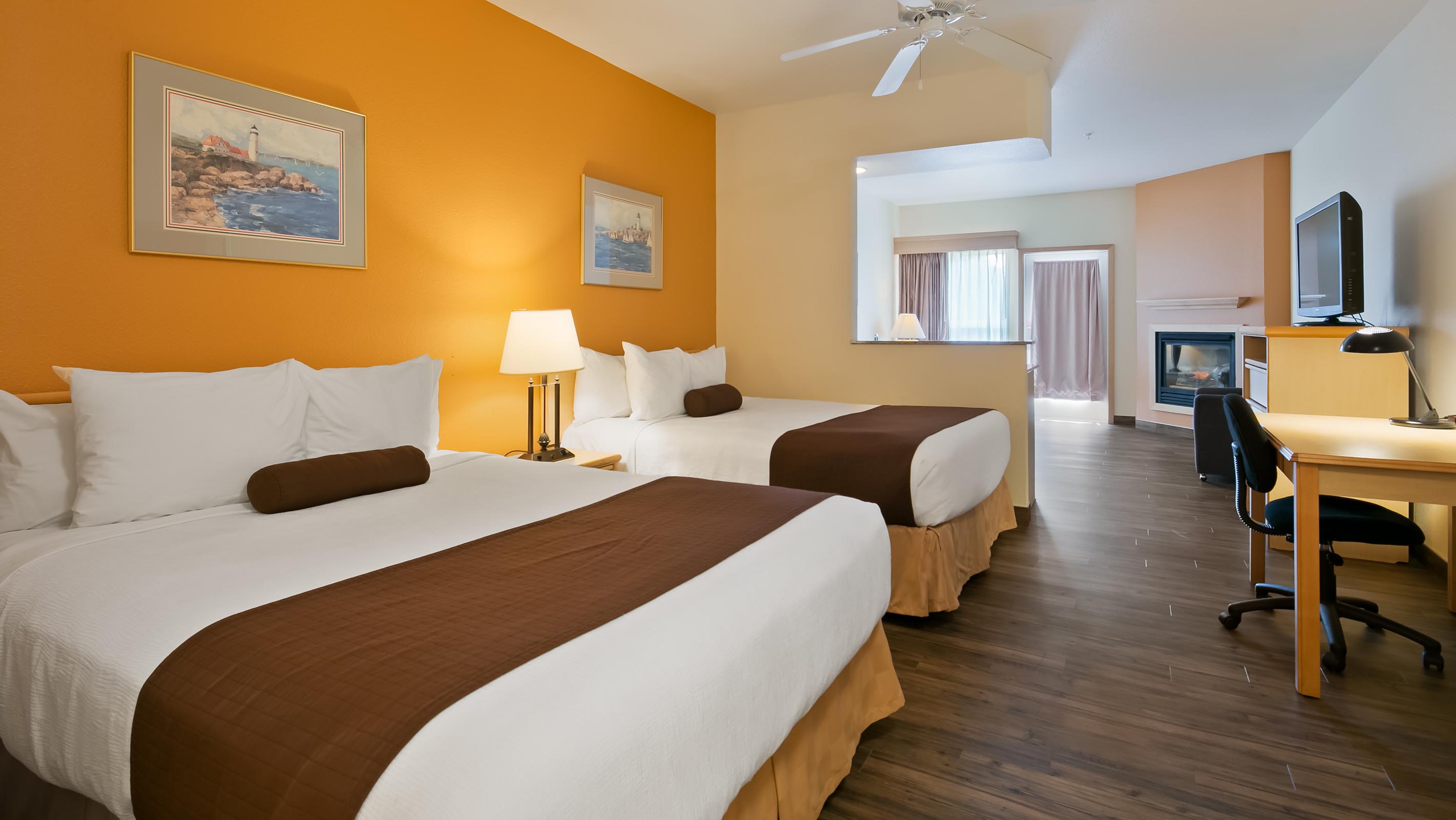 Two queen beds with work desk and orange wall